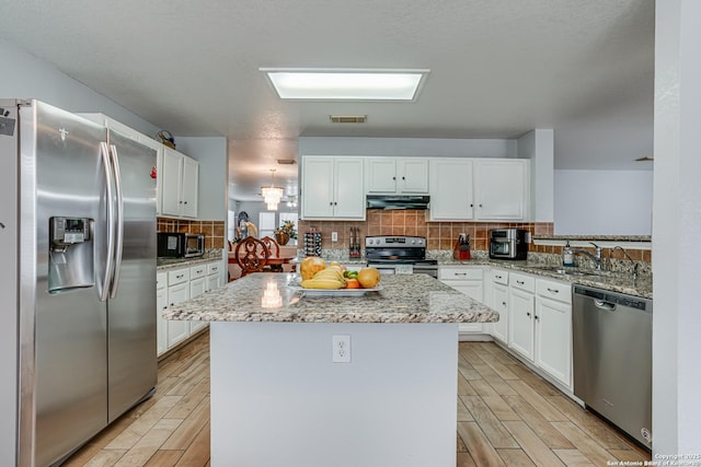 kitchen with visible vents, wood finish floors, a sink, stainless steel appliances, and under cabinet range hood