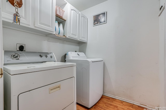 clothes washing area featuring cabinet space, light wood-style flooring, and washing machine and dryer