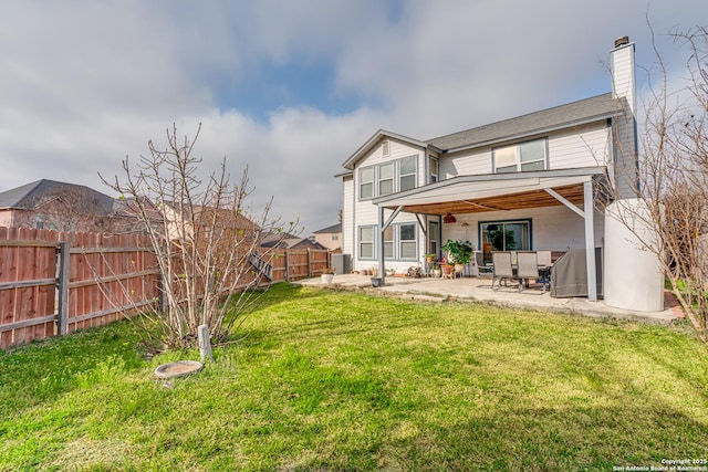 back of property with a yard, a patio area, a fenced backyard, and a chimney