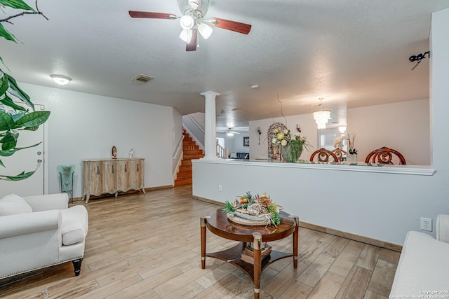 living room with stairway, light wood-style floors, and a ceiling fan