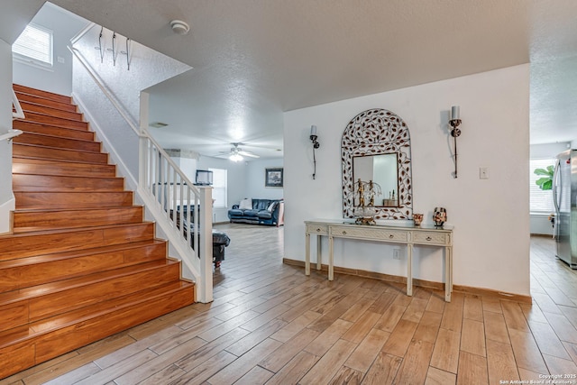 interior space featuring a wealth of natural light, a textured ceiling, a ceiling fan, and wood finished floors