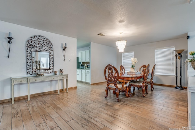 dining area with visible vents, baseboards, a chandelier, and light wood finished floors