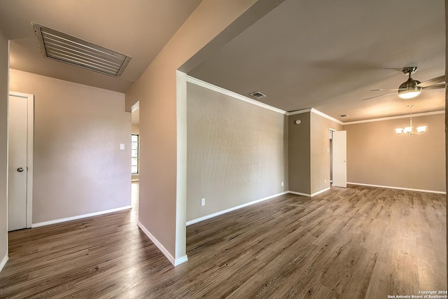 spare room featuring ceiling fan with notable chandelier, crown molding, wood finished floors, and baseboards