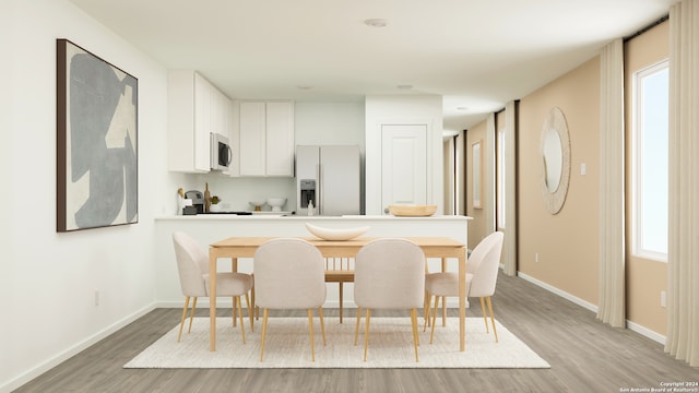 kitchen featuring light wood-type flooring, fridge with ice dispenser, baseboards, and white cabinetry