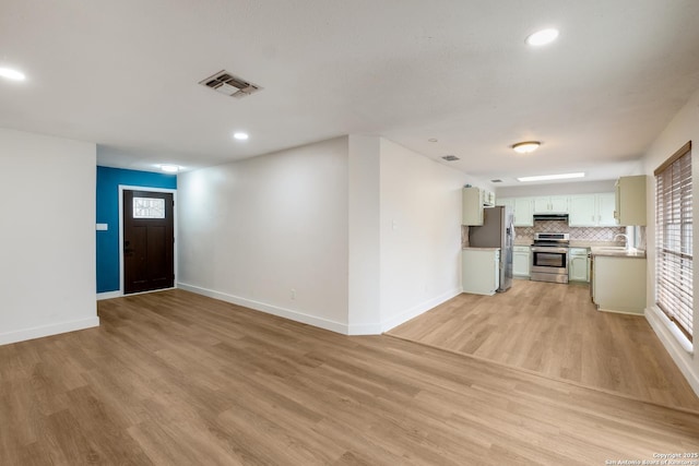 interior space with visible vents, baseboards, light wood-style floors, and a sink