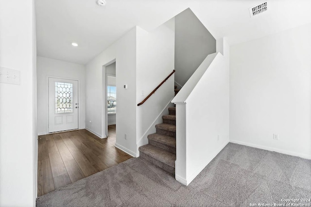 carpeted foyer entrance featuring visible vents, baseboards, stairs, recessed lighting, and wood finished floors