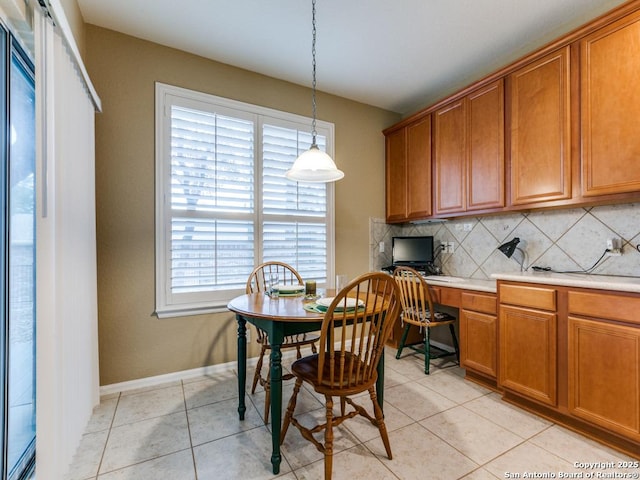 dining space with light tile patterned floors, baseboards, and built in desk