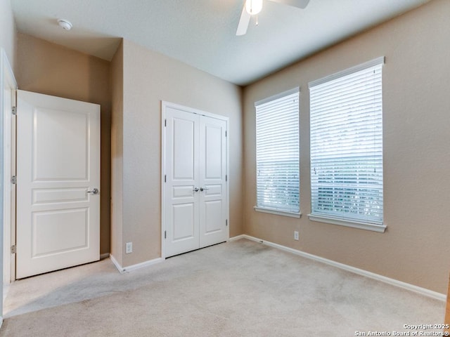 unfurnished bedroom with a ceiling fan, baseboards, a closet, and light carpet