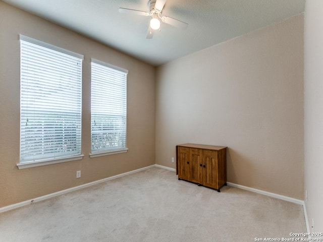 carpeted empty room with a ceiling fan and baseboards