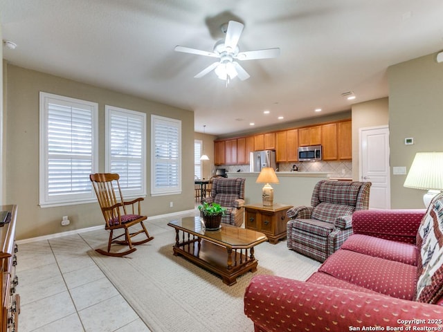 living area with light tile patterned floors, a healthy amount of sunlight, baseboards, and ceiling fan