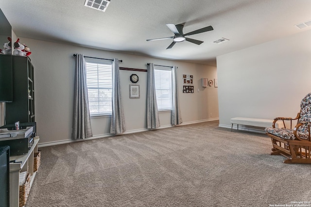 living area featuring carpet, visible vents, and ceiling fan