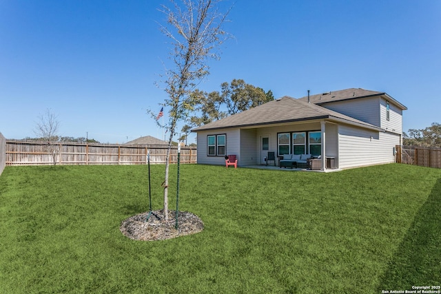 rear view of property featuring a patio, a yard, a fenced backyard, and roof with shingles