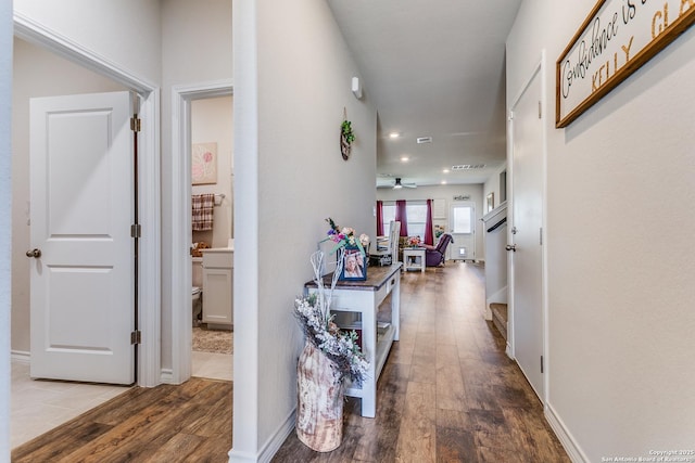 hallway with visible vents, baseboards, and wood finished floors