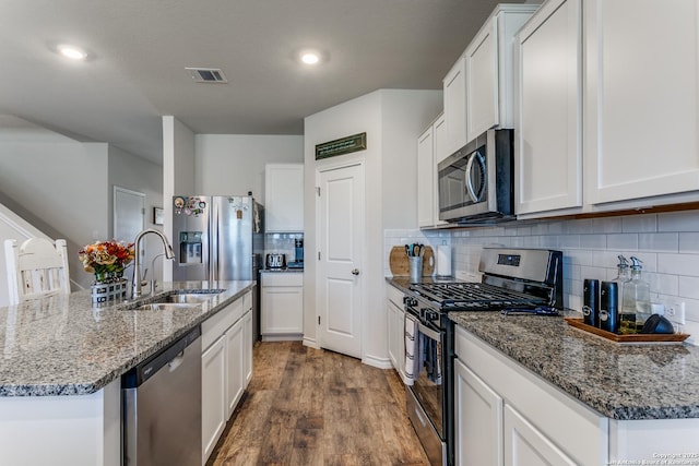 kitchen featuring visible vents, dark wood finished floors, a sink, decorative backsplash, and appliances with stainless steel finishes