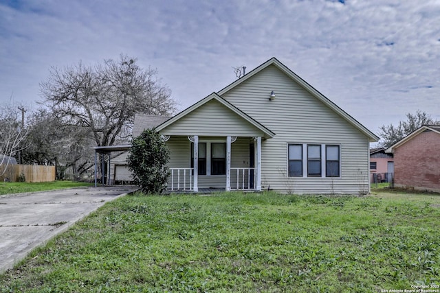 bungalow featuring fence, a porch, an attached garage, concrete driveway, and a front lawn