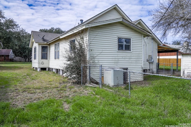 view of side of home with a carport, central AC unit, a lawn, and fence