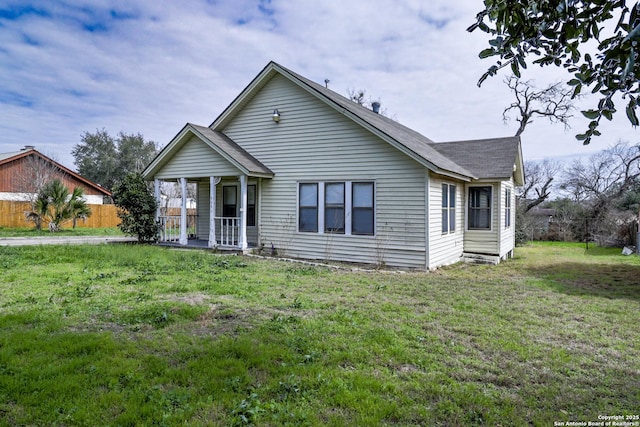 view of front of home featuring a front yard, a porch, fence, and a shingled roof