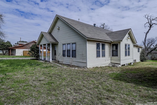 view of front facade with roof with shingles and a front lawn