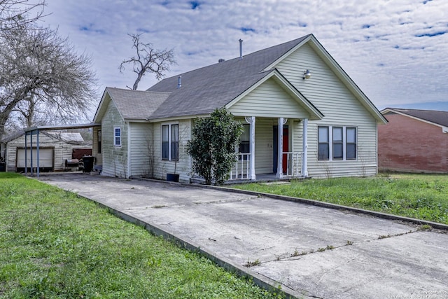 view of front of home with a porch, a front yard, a garage, an outdoor structure, and driveway