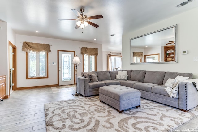 living room with a wealth of natural light, visible vents, a ceiling fan, and wood finished floors