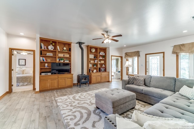 living area featuring recessed lighting, light wood-type flooring, a wood stove, and a ceiling fan