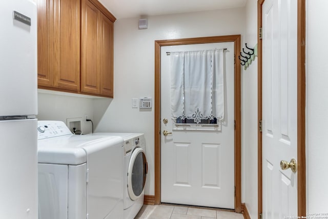 washroom with washer and dryer, light tile patterned flooring, and cabinet space