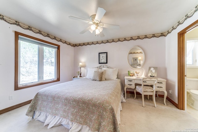 bedroom with connected bathroom, light colored carpet, baseboards, and ceiling fan