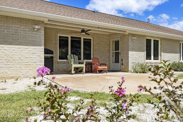 back of property with a ceiling fan, a patio area, brick siding, and roof with shingles