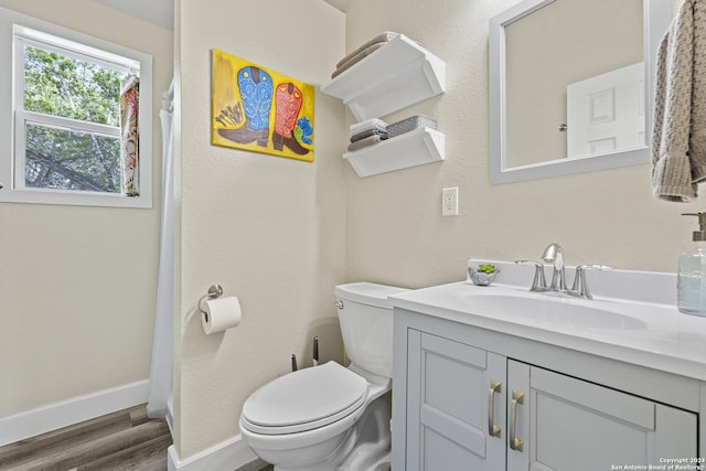 bathroom with baseboards, toilet, wood finished floors, and vanity