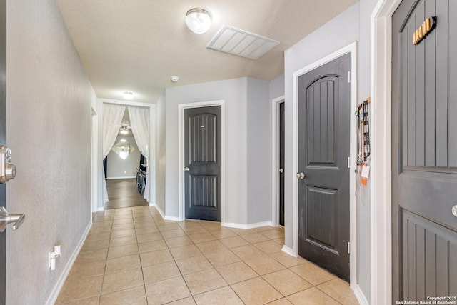 foyer entrance with visible vents, baseboards, and light tile patterned flooring