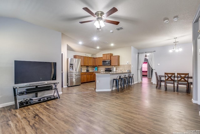 kitchen featuring stainless steel appliances, lofted ceiling, a peninsula, and ceiling fan with notable chandelier