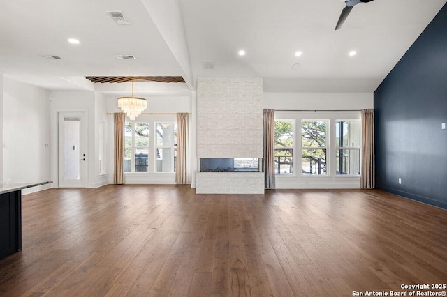 unfurnished living room with a brick fireplace, recessed lighting, visible vents, and dark wood-style flooring