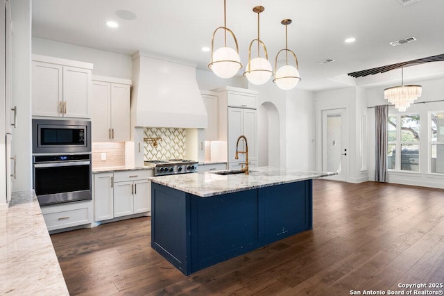 kitchen with visible vents, arched walkways, stainless steel appliances, custom range hood, and tasteful backsplash