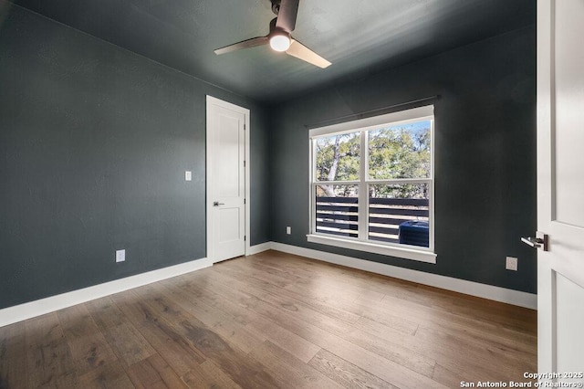 empty room with wood finished floors, baseboards, and ceiling fan