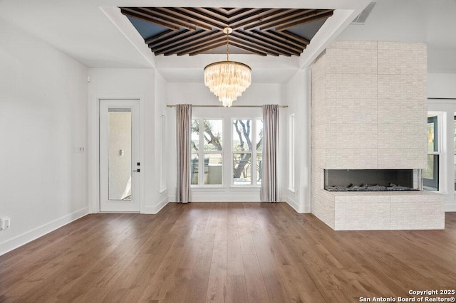 foyer featuring visible vents, a notable chandelier, coffered ceiling, wood finished floors, and a multi sided fireplace