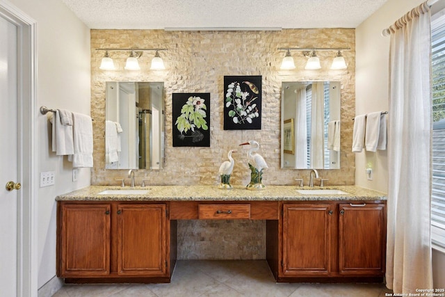 full bathroom featuring double vanity, plenty of natural light, a textured ceiling, and a sink