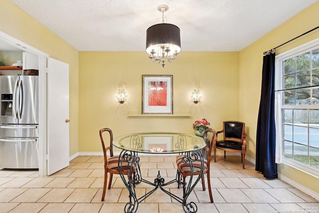 dining space with a chandelier, a textured ceiling, and baseboards