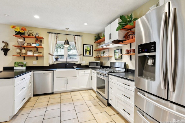 kitchen featuring open shelves, stainless steel appliances, dark countertops, and a sink