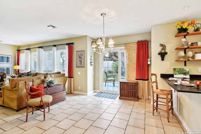 interior space featuring an inviting chandelier, light tile patterned floors, visible vents, and a wealth of natural light