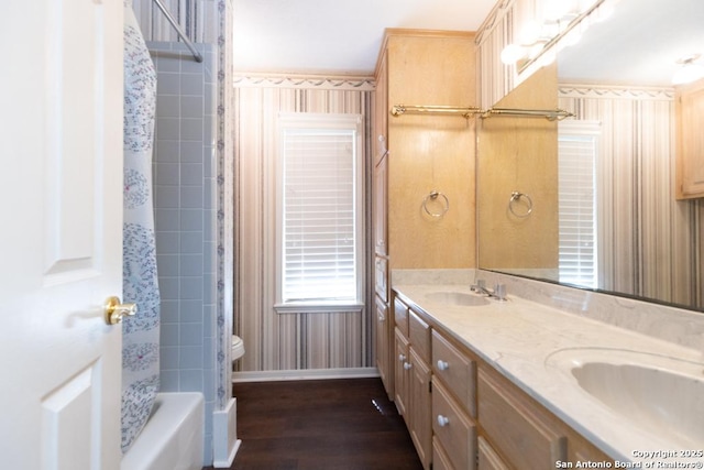 full bath with double vanity, wood finished floors, baseboards, and a sink