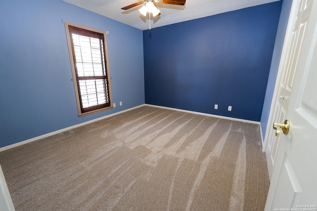 carpeted spare room featuring baseboards and ceiling fan