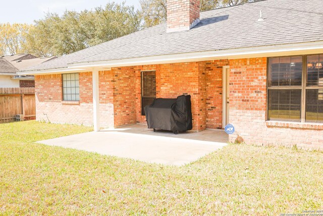 back of property featuring a patio, fence, a shingled roof, brick siding, and a chimney