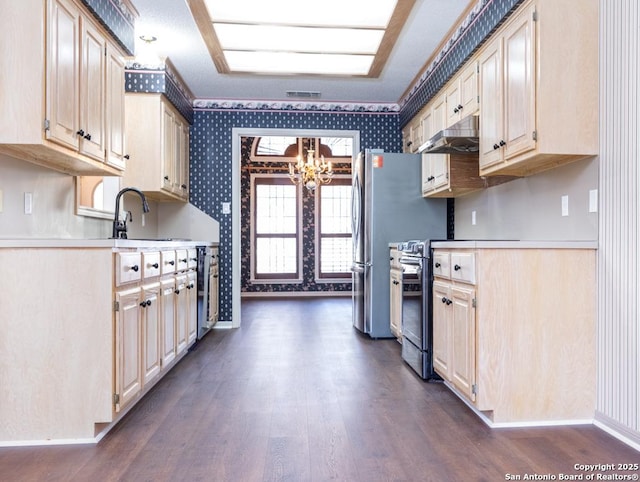 kitchen with under cabinet range hood, wallpapered walls, stainless steel appliances, and a sink