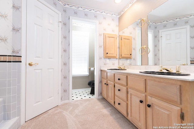 full bathroom with a sink, wallpapered walls, baseboards, and double vanity