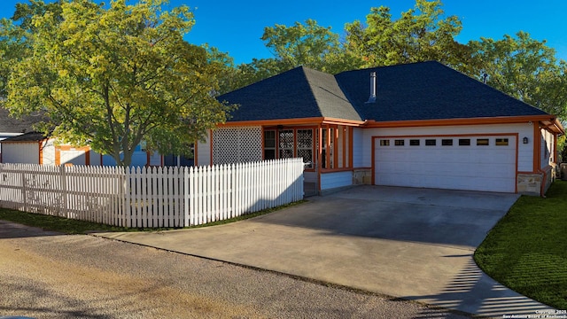 view of front of property with stone siding, fence private yard, concrete driveway, and an attached garage