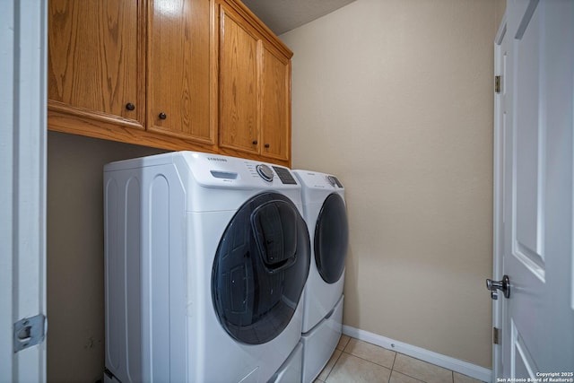 clothes washing area featuring washing machine and clothes dryer, cabinet space, baseboards, and light tile patterned flooring