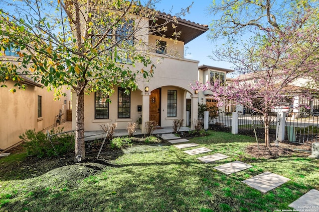 mediterranean / spanish-style house featuring a fenced front yard, a porch, a front yard, stucco siding, and a balcony