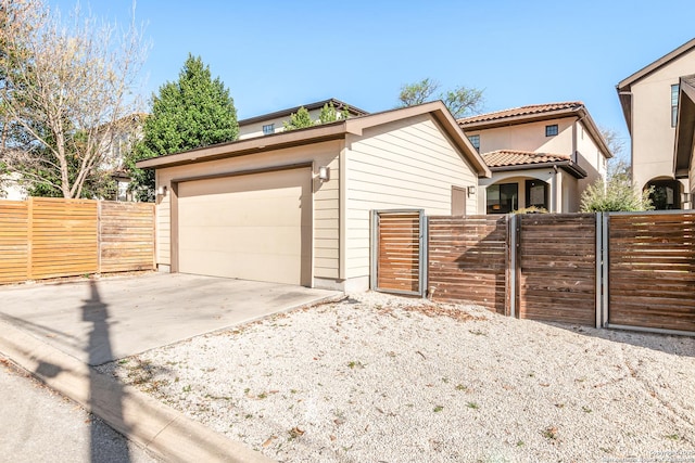 view of front of property featuring a gate, fence, a garage, and driveway