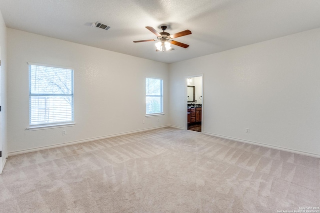 unfurnished room featuring visible vents, baseboards, carpet, a textured ceiling, and a ceiling fan