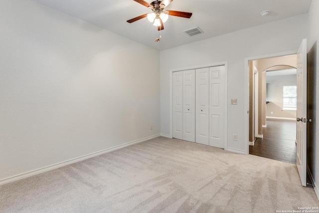 unfurnished bedroom with visible vents, baseboards, a closet, carpet floors, and arched walkways